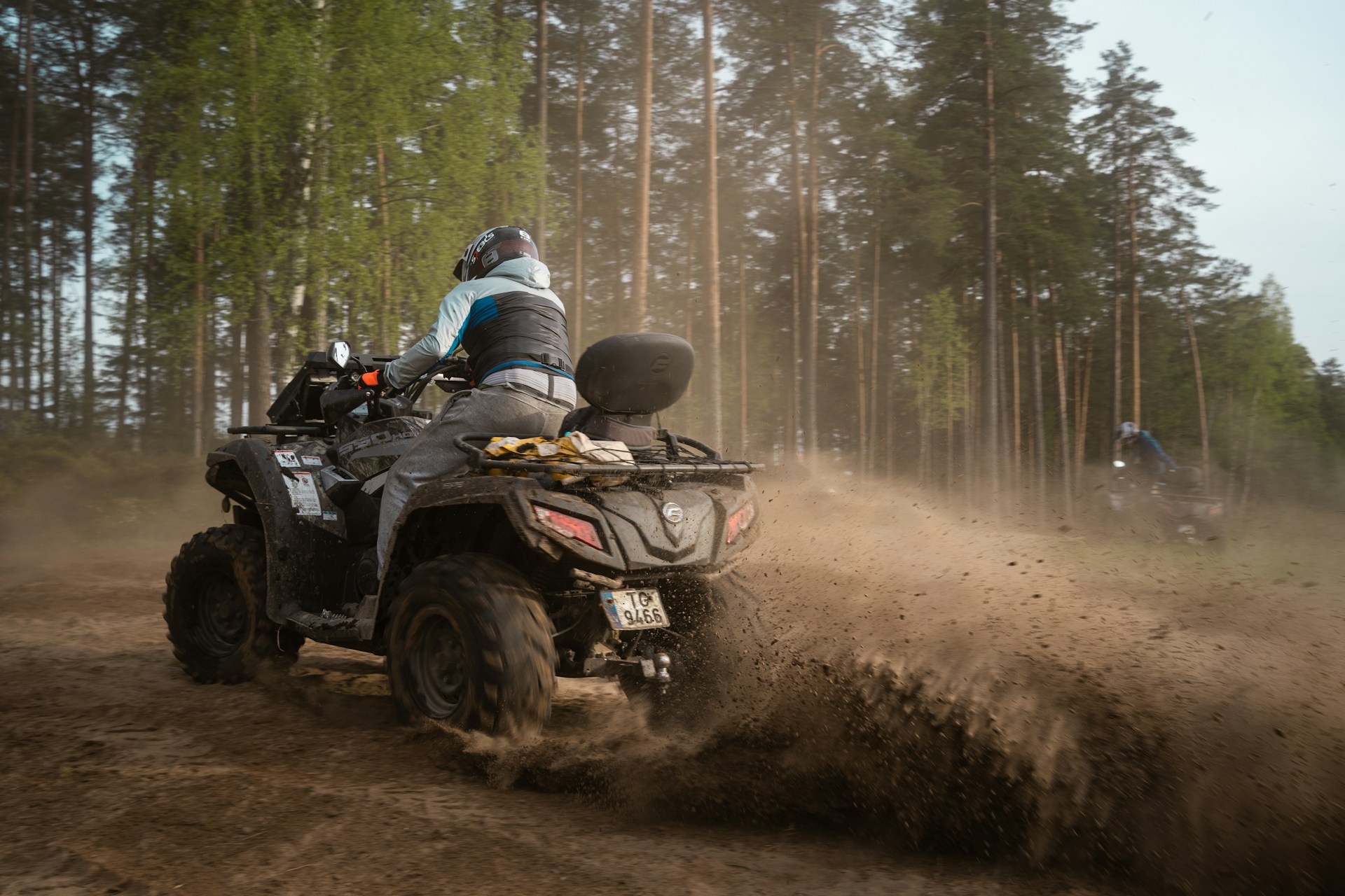 ATV kicking up dust on a forest trail